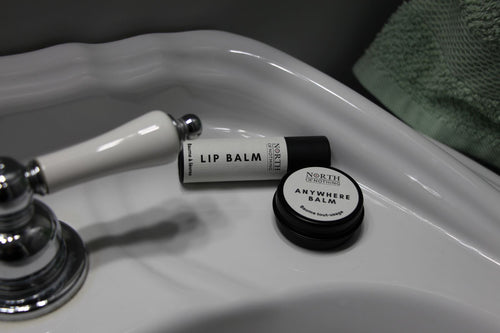 North of Nothing Lip Balm and Anywhere Balm displayed on a bathroom sink.