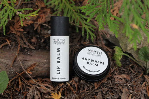 North of Nothing Lip Balm and Anywhere Balm displayed outdoors on a forest floor.